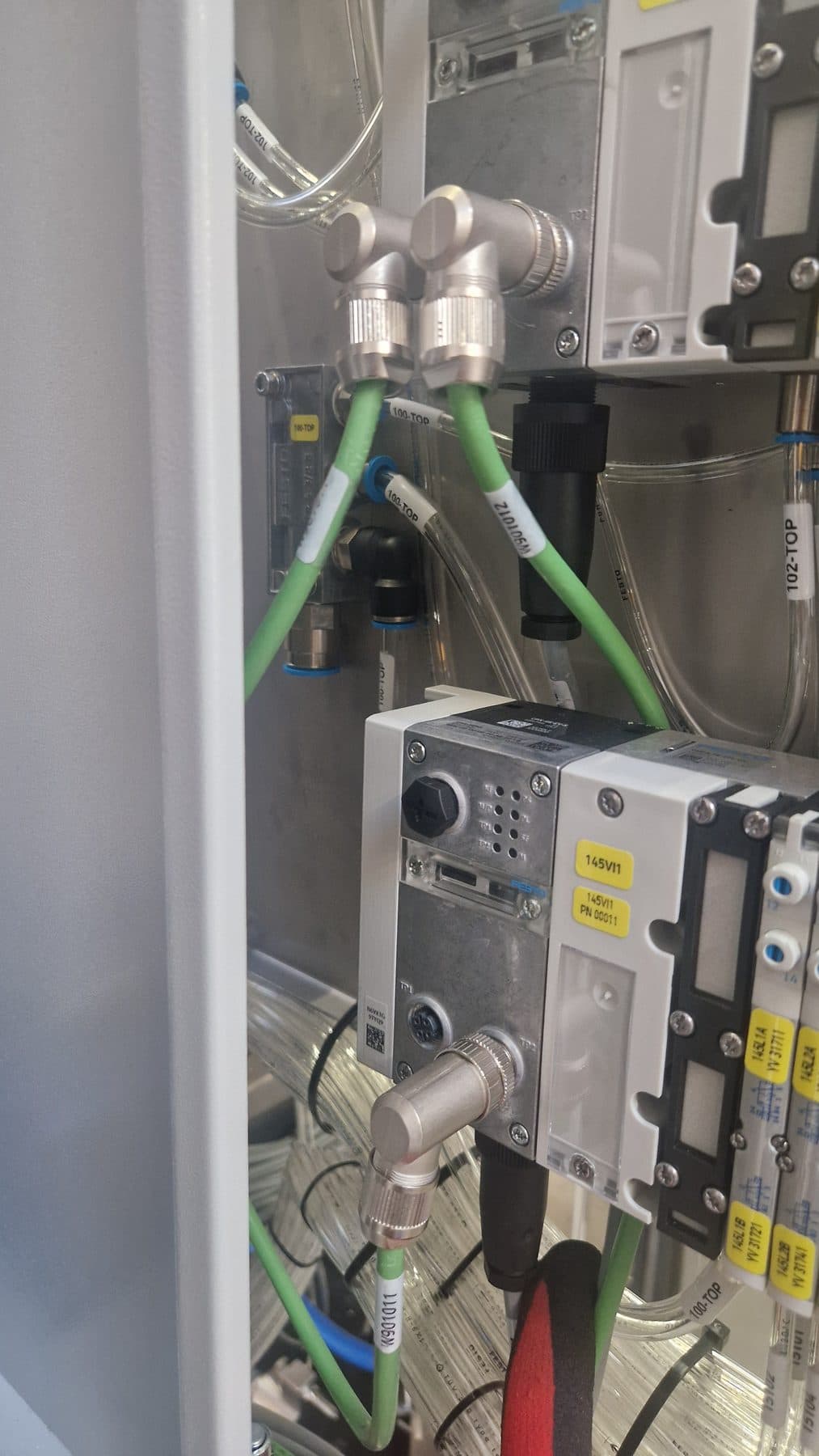 Zielone przewody z wtykami M12 i opisami przy module zaworowym